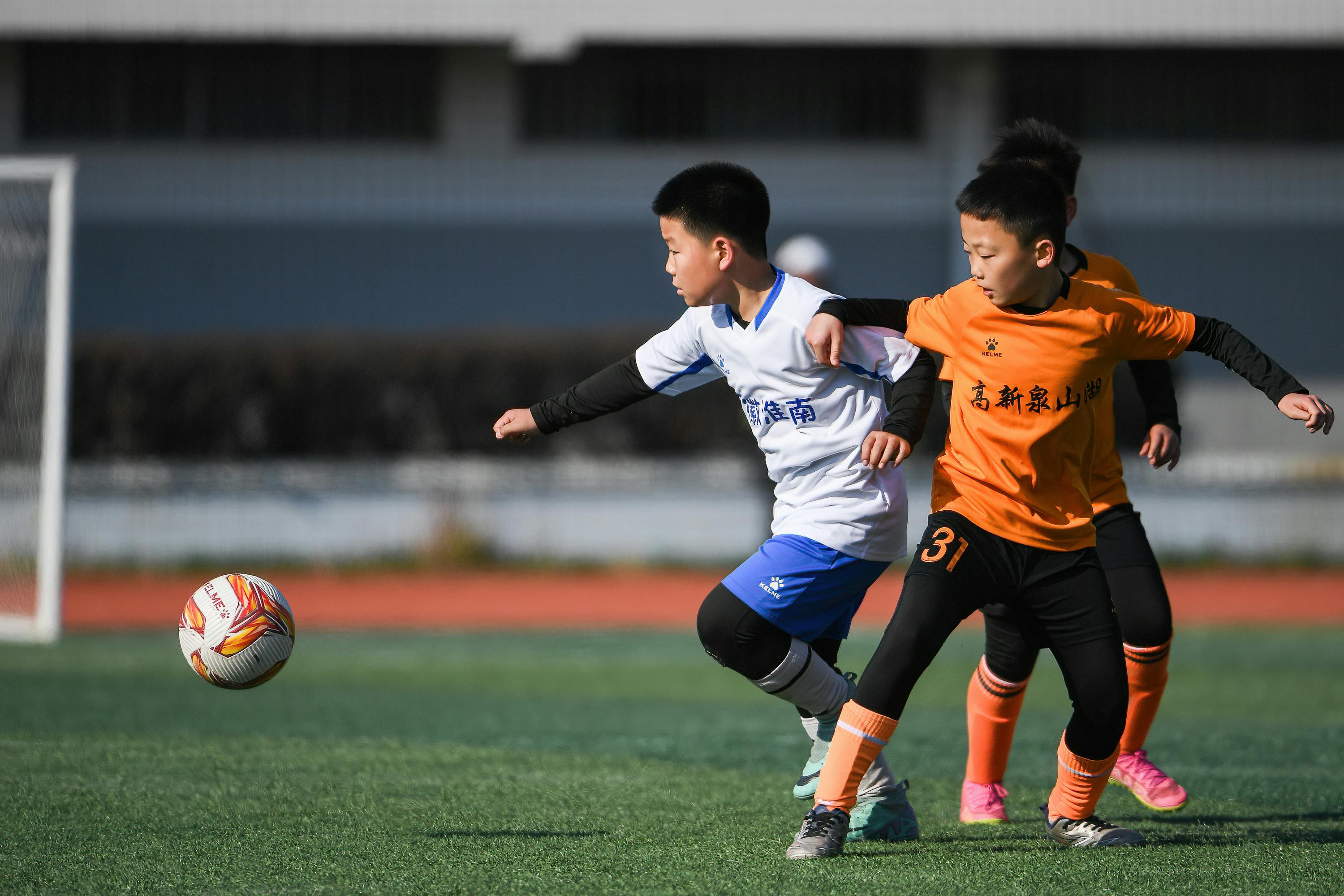 Primary school boys playing football on school field funded by PE and sport premium